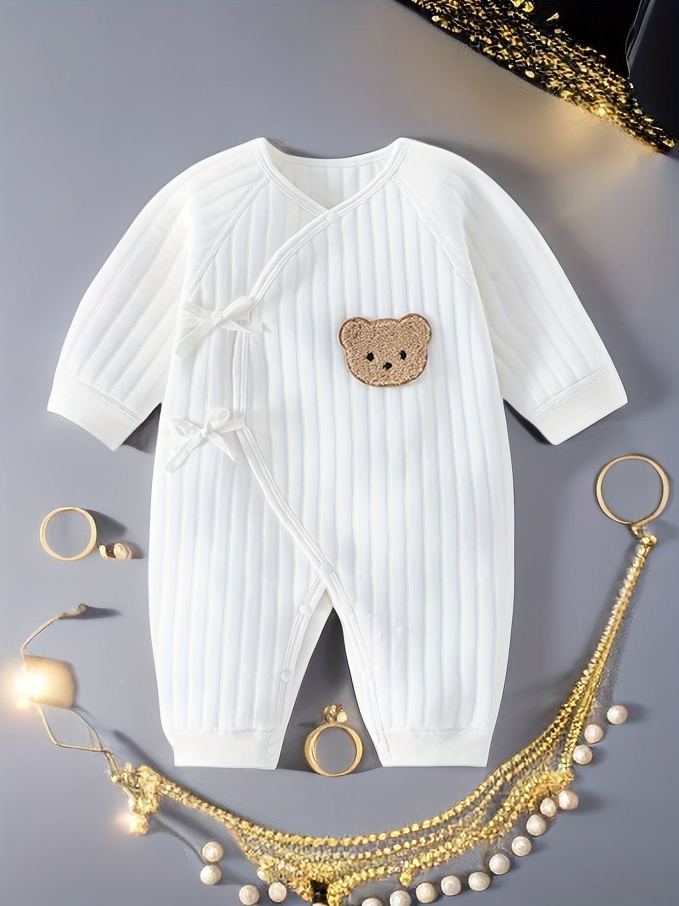 Baby romper featuring a playful bear patch, made from soft cotton for breathability during fall and winter, designed for easy dressing with bows and buttons. 0